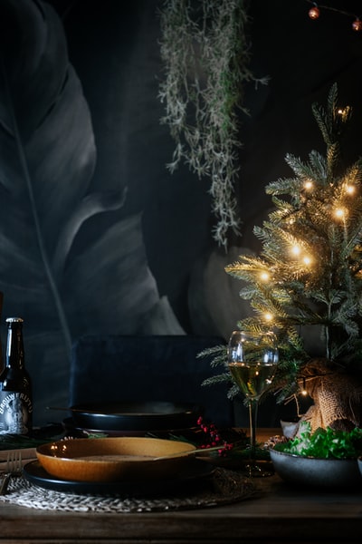 黑色桌子旁的绿色圣诞树上开着串灯
